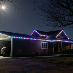A house is lit up with colourful permanent outdoor lighting with red, blue green and white Christmas lighting